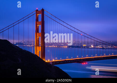Vista dalla pastella Spencer al Golden Gate bridge con calda luce riflettendo alla superficie dell'acqua di San Francisco all'alba. Foto Stock