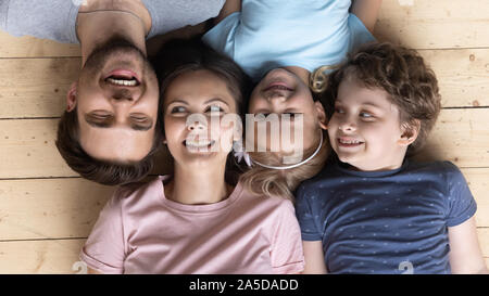 Ritratto di sorridere i genitori con bambini che giace sul pavimento in legno Foto Stock