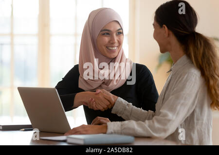 Felice femmina musulmani asiatici manager caucasici di handshaking lady client Foto Stock