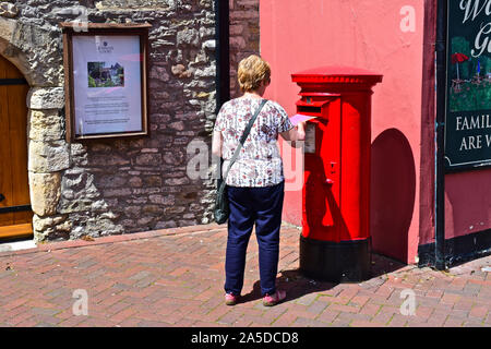 Donna Inviare lettera nel tradizionale rosso postbox nel vecchio quartiere di Poole Quay su una soleggiata giornata estiva. Accanto al re la testa public house. Foto Stock