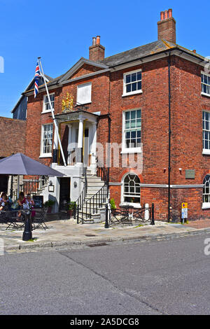 Il Custom House Café sulla banchina nel vecchio porto di Poole, con vedute del porto. Le persone che si godono il sole estivo seduta al di fuori di questa casa storica. Foto Stock