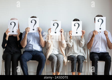 Imprenditori disoccupati nascondendo la faccia con domande in attesa per il colloquio di lavoro Foto Stock