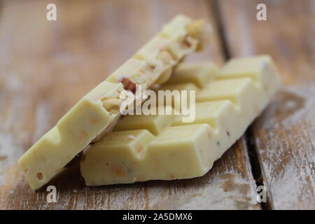 Due grandi pezzi di cioccolato bianco con nocciole rustico superficie in legno Foto Stock