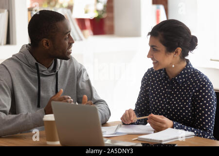 Ragazzo africano ragazza indiana seduti alla scrivania facendo attività comune Foto Stock
