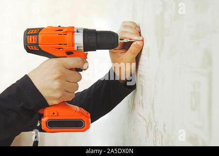 Concetto. Lavoratore è avvitando la vite di muretti a secco mediante vite di pistola alla parete di cartongesso in appartamento è in costruzione, ristrutturazione, restauro, overha Foto Stock