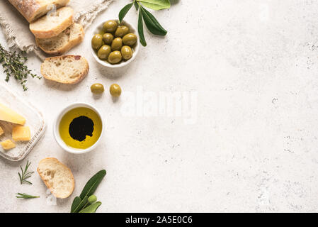 Cucina mediterranea a sfondo. Italiani freschi ciabatta pane alle erbe aromatiche, olio d'oliva, aceto balsamico, parmigiano e olive su sfondo bianco, vista dall'alto Foto Stock