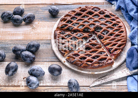 Close-up in casa deliziosa torta con prugne su un sfondo rustico. Foto Stock