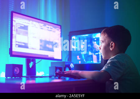 Ragazzo giocare con il gioco sul gaming computer hacking o un sito web concetto. Scena scura con un sacco di illuminazione RGB. Foto Stock