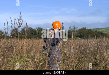 Worthing, Regno Unito. Xx oct, 2019. Una donna porta la sua zucca sul suo capo a scegliere il proprio centro di zucca al Sompting vicino a Worthing in West Sussex su una graziosa soleggiata giornata autunnale . Credito: Simon Dack/Alamy Live News Foto Stock