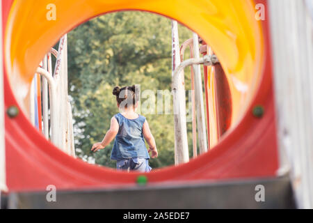 Retro di una ragazzina di divertirsi nel parco giochi bambini, attività di svago di apparecchiature Foto Stock