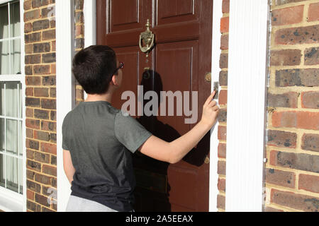 Bambino squilla il campanello della porta anteriore, numero 3, indossando occhiali, marrone porta, Georgian House, REGNO UNITO Foto Stock