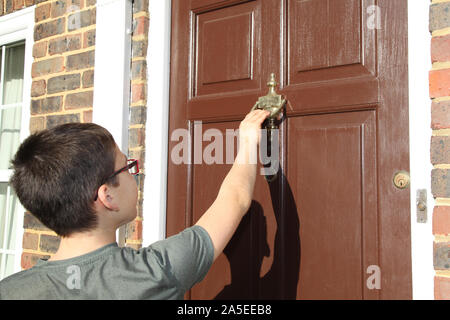 Bambino a bussare alla porta anteriore, numero 3, indossando occhiali, marrone porta, Georgian House, REGNO UNITO Foto Stock