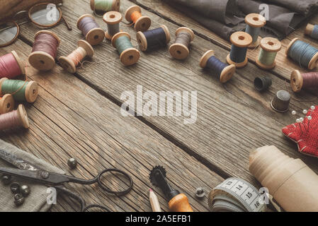 Vintage elementi di cucitura: retro sartoria forbici, nastro di misurazione, ditale, legno rocchetti di filato, modelli su carta, il coltello di taglio, cuscino per ch. Foto Stock