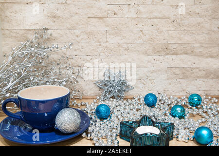 Cacao caldo con il latte nella tazza blu. Argento e blu decorazioni di Natale, come argento perle e palle di Natale. Il simbolo del fiocco di neve in argento e turchese star-sha Foto Stock