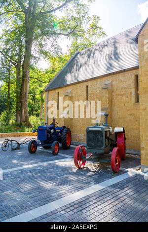 Vintage trattori e macchinari agricoli al di fuori del granaio di trebbiatura presso il recentemente restaurato "Il Tritone in Somerset' giardino e hotel, nr Bruton, England, Regno Unito Foto Stock