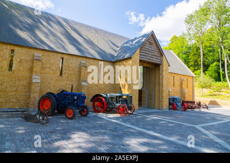 Vintage trattori e macchinari agricoli al di fuori del granaio di trebbiatura presso il recentemente restaurato "Il Tritone in Somerset' giardino e hotel, nr Bruton, England, Regno Unito Foto Stock