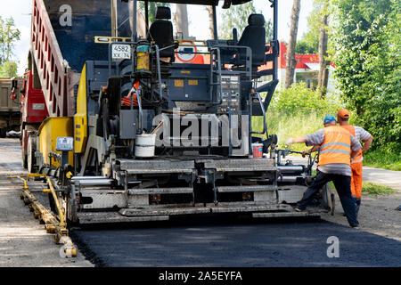 La regione di Celjabinsk, Russia - Agosto 2019. Nuovo lastricatore in azione. Riparazione su strada. Asfalto da pavimentazione. La posa di un nuovo strato di asfalto Foto Stock