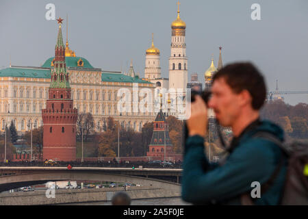 Un uomo è fotografata sul ponte Patriarshy sullo sfondo del Cremlino a Mosca, Russia Foto Stock
