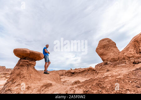 L'uomo escursionista sulla parte superiore dell unico hoodoo arenaria formazioni di roccia il paesaggio del deserto in Goblin Valley State Park in Utah sul sentiero Foto Stock