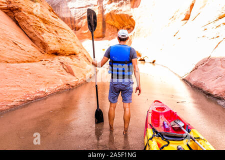 Kayak Trekking trail nel Lago Powell stretti e bassi Antelope Canyon con uomo con pagaia remo in piedi sporchi acqua fangosa e formazioni rocciose Foto Stock