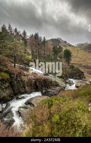 Bella immagine di panorama di Ogwen Valle del fiume e cascate durante il periodo invernale con cime innevate sullo sfondo Foto Stock