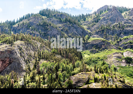 Basso angolo vista sul verde picco di montagna e Cielo e nubi nei pressi di Ouray, Colorado con San Juan montagne rocciose in estate e gli alberi da milioni di dollari di Highwa Foto Stock