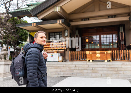 Tokyo, Giappone Togo Shrine Temple exterior edificio ingresso con felice uomo turistica permanente sulla strada in Shibuya Harajuku Foto Stock