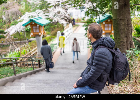 Tokyo, Giappone Togo santuario il giardino del tempio con un turista uomo seduto sulla ringhiera di passi sulla strada in Shibuya Harajuku con persone di background Foto Stock
