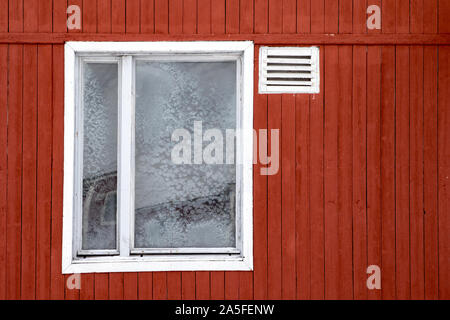 Pyramiden, Norvegia - Agosto 2017: finestra congelata in un vecchio dipinto di rosso edificio abbandonato in Pyramiden nell arcipelago delle Svalbard. Foto Stock