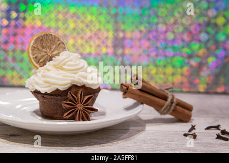 Holiday cupcake con glassa di mascarpone, essiccate di agrumi, arancio, limone e decorazione di calce, i chiodi di garofano, cimmanon rotoli e anice stelle. Luminose colorate bac Foto Stock