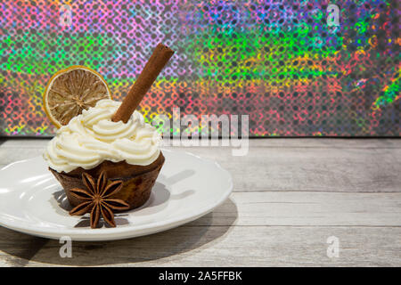 Holiday cupcake con glassa di mascarpone, essiccate di agrumi, arancio, limone e la calce e decorazione, cimmanon rotoli e anice stelle. Luminoso dello sfondo colorato. Foto Stock