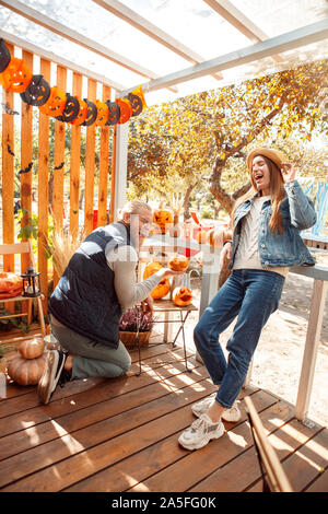 Halloween Preparaton concetto. Coppia giovane decorare casa con jack-o-lantern ridendo allegro Foto Stock