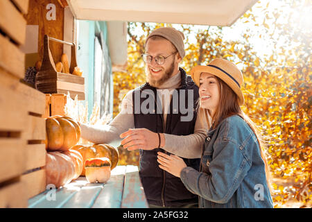 Halloween Preparaton concetto. Coppia giovane decorare casa con zucche sorridendo felice Foto Stock
