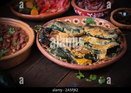 Chilles rellenos servita nei tradizionali piatti messicani, servito con fagioli, sottaceti Foto Stock