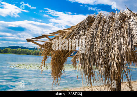 Ombrellone in spiaggia, lucido giornata con cielo blu. Concetto di relax. Dnipro river. Foto Stock