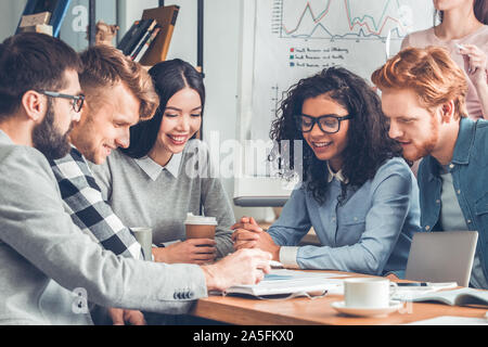Startupers lavorando insieme a Office seduta la progettazione del piano di progetto gioiosa alla ricerca di documenti Foto Stock