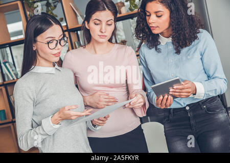 Startupers femmina lavorando insieme a Office in piedi che guarda al contratto discutendo concentrata Foto Stock