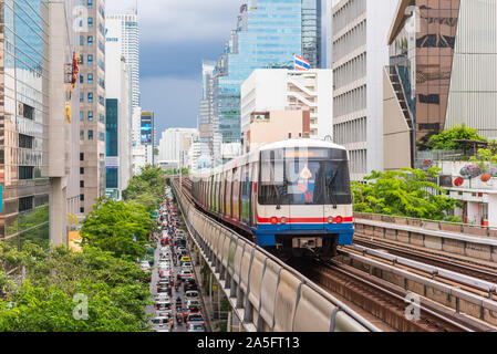 Bangkok, Tailandia - 25 Giugno 2019: un BTS treno in partenza Stazione Sala Daeng sopra il traffico della strada sulla Silom Road. Foto Stock