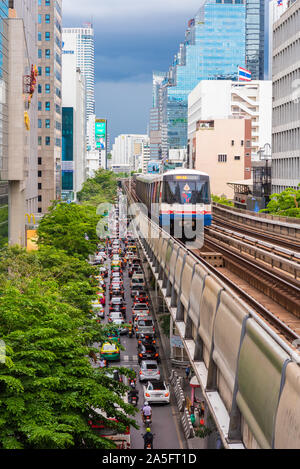 Bangkok, Tailandia - 25 Giugno 2019: un BTS treno in partenza Stazione Sala Daeng sopra il traffico della strada sulla Silom Road. Una versione verticale. Foto Stock
