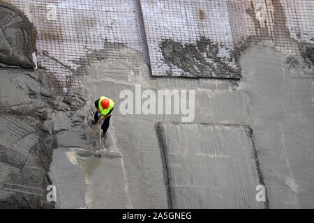 Lavoratore versare cemento presso il cantiere, vista dall'alto. Installazione di supporti per la fondazione di edificio, posa in opera di lastre di cemento Foto Stock