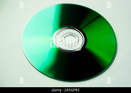 Un disco DVD che appare di colore verde nella luce del sole da windows è su sfondo bianco Foto Stock