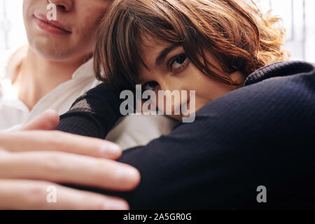 Close-up immagine della giovane donna appoggiata sulla spalla del suo ragazzo e guardando la fotocamera Foto Stock