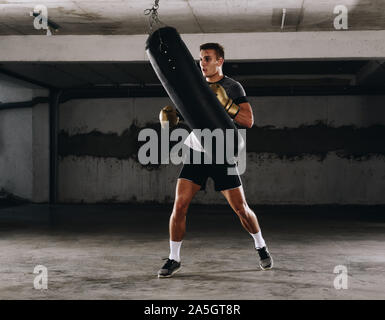 Giovane uomo in guantoni da pugilato. Il pugilato uomo pronto a combattere. Il pugilato, allenamento, muscolo, forza, potenza - il concetto di forza di formazione Foto Stock