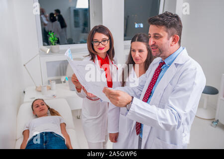 Il gruppo di medici in piedi accanto a un malato e discutere le cause per la sua malattia. Foto Stock