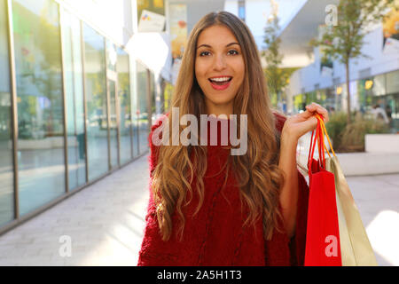 Felice Allegra donna con red poncho holding borse per lo shopping nel centro commerciale della citta'. Foto Stock