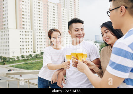 Giovani popoli asiatici godendo di partito sul tetto e tostatura con bicchieri di champagne Foto Stock