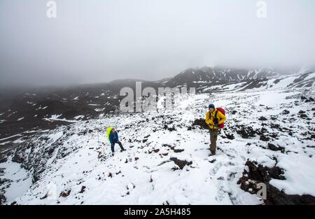 Gli escursionisti sul sentiero escursionistico Tongariro Alpine Crossing nella neve per i campi di lava del Parco Nazionale di Tongariro, Isola del nord, Nuova Zelanda Foto Stock