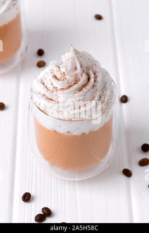 Latte macchiato di zucca con panna e spezie in bianco sullo sfondo di legno Foto Stock