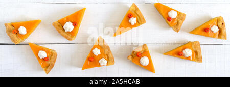 Pezzi della tradizionale torta di zucca su un bianco sullo sfondo di legno. Tema del ringraziamento. Cibo sano, dessert per buongustai. Tradizionale autunno snack. Bann Foto Stock