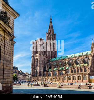 La guglia della cattedrale di Notre Dame a Strasburgo, Francia, con persone che passeggiano sulla place du Chateau e il Palazzo Rohan in primo piano. Foto Stock